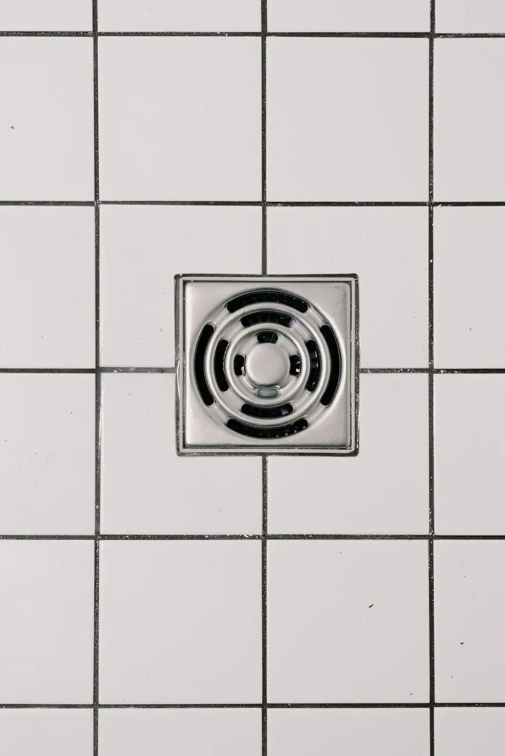 Shower drain in a tiled bathroom, blocked drain signs checked by The Drain Masters